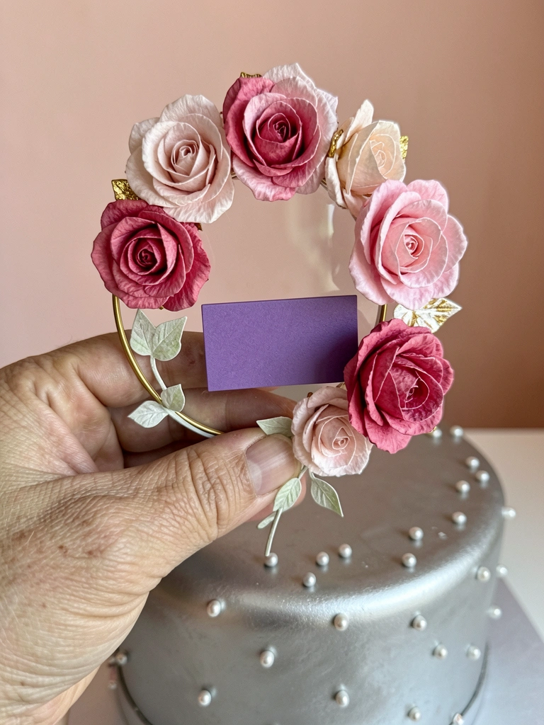 Bolo de andar único com cobertura lisa, pérolas comestíveis e detalhes metálicos brilhantes sobre mesa clara