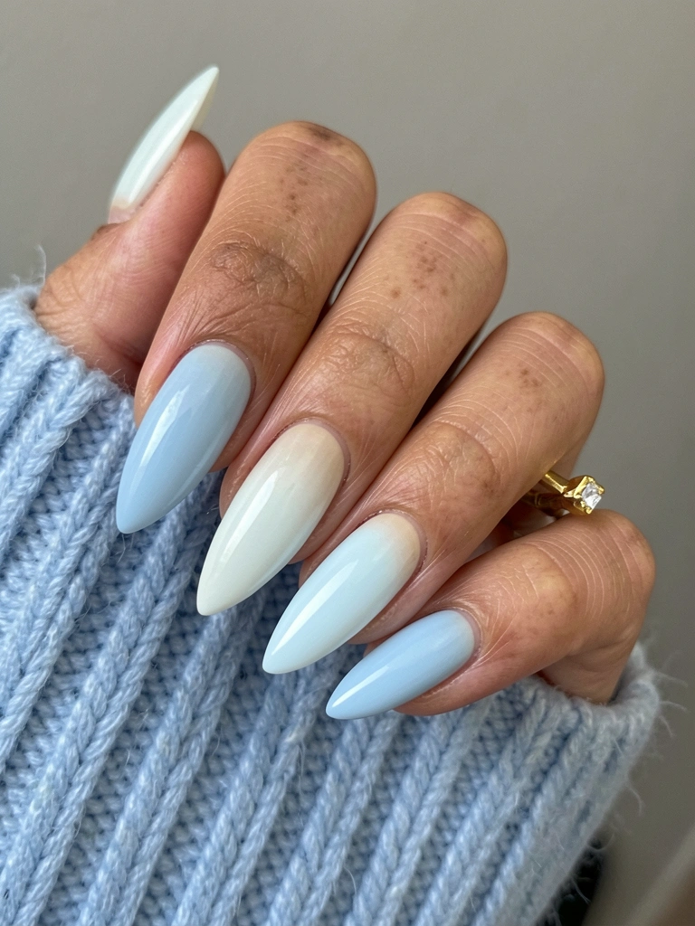 Duas unhas postiças lado a lado: uma com esmalte azul leitoso e outra com azul pastel cremoso.