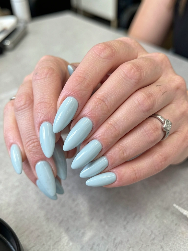 Unhas amendoadas pintadas com esmalte azul claro de acabamento cremoso