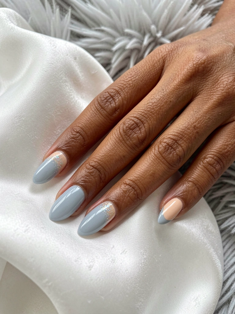 Mãos sobre superfície clara com unhas pintadas em tom azul claro e anel fino dourado.